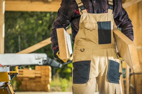 Builder Contractor with Wood Beams in Hands. Wooden Frame House Building.