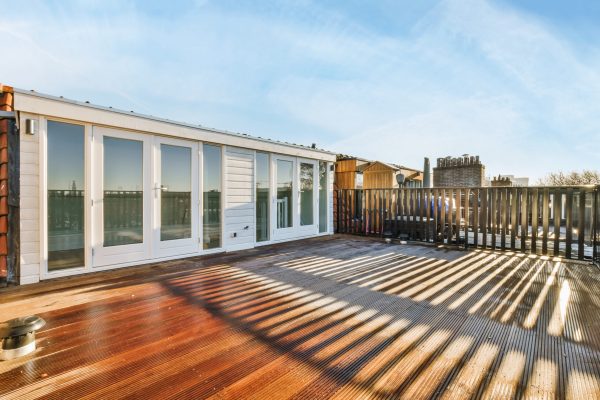 Design of a large balcony with wooden floor and black metal handrails